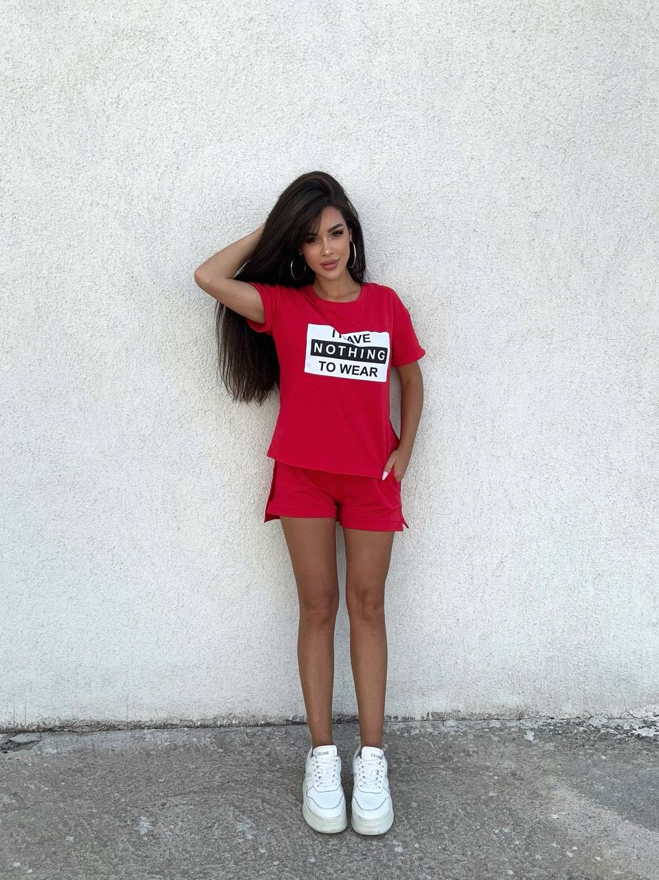 Person wearing a red outfit with a graphic t-shirt against a white wall.