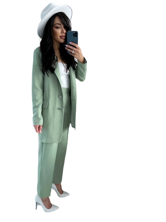 Woman in a green suit and white hat taking a selfie on a white background