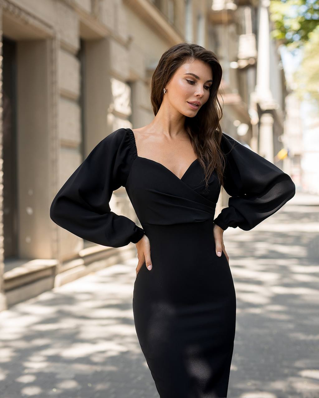 Woman wearing a black dress with puffed sleeves on a city street.