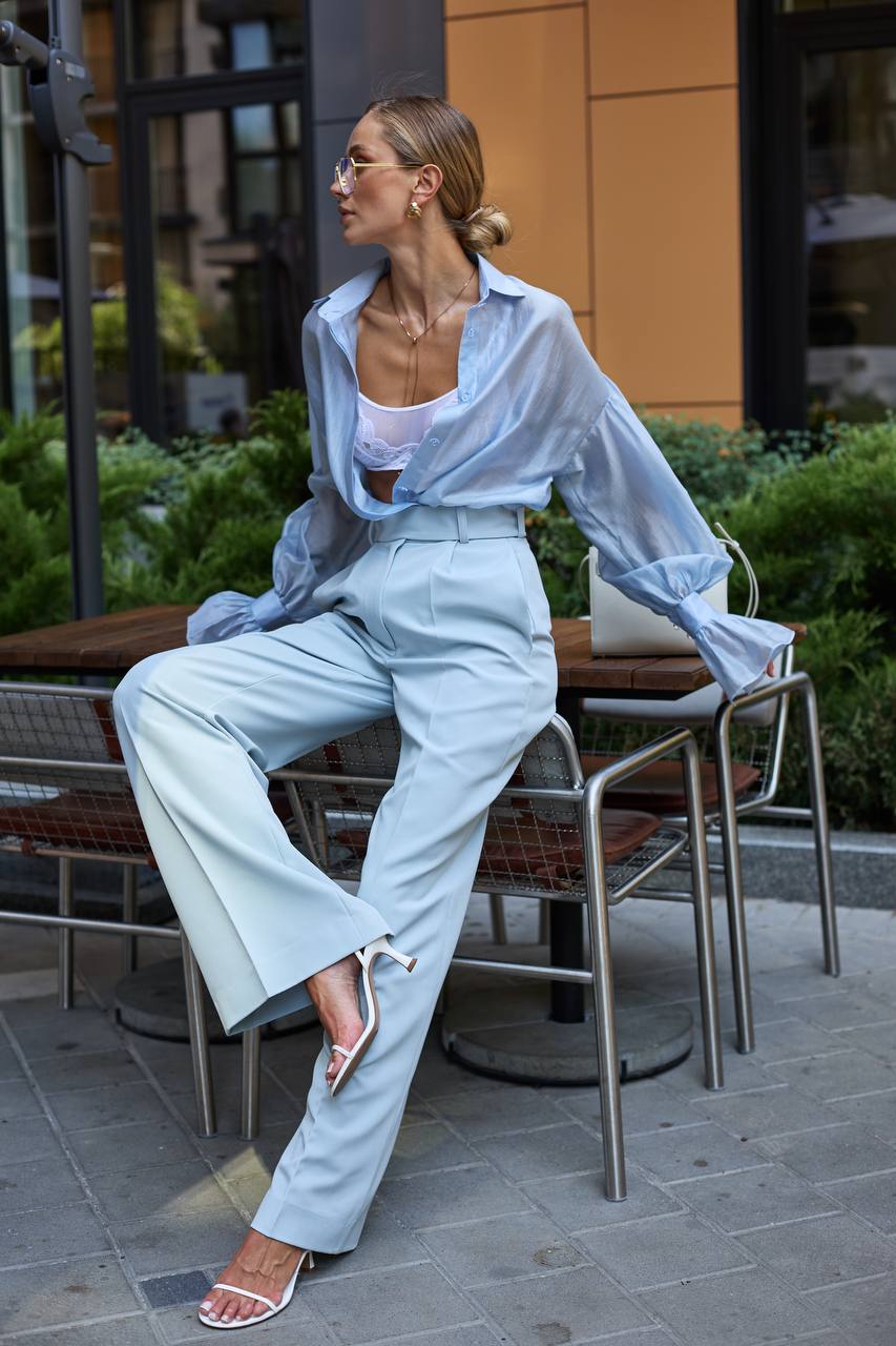 Woman in light blue outfit sitting outdoors on a chair.