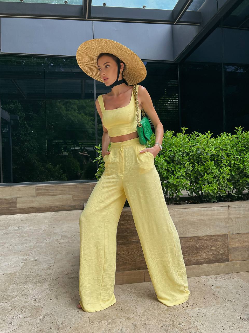 Woman in yellow outfit with wide-brimmed hat standing outdoors.