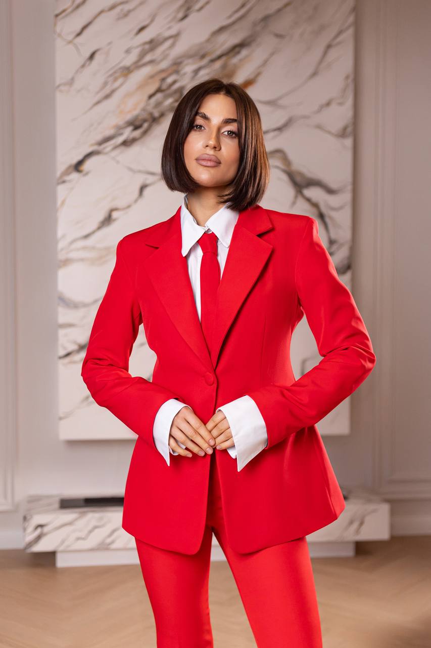 Woman wearing a red suit with a white shirt in an indoor setting