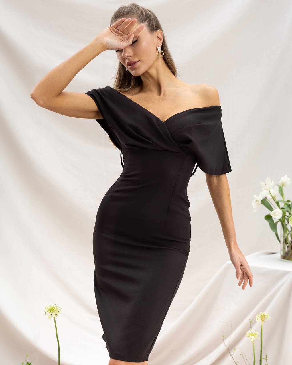 Woman wearing a black off-shoulder dress against a white background