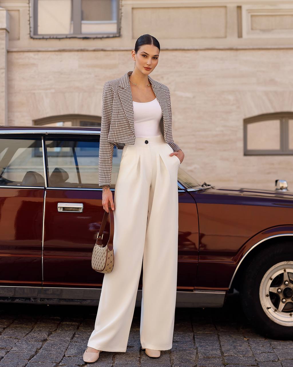Woman in a stylish outfit standing next to a vintage car