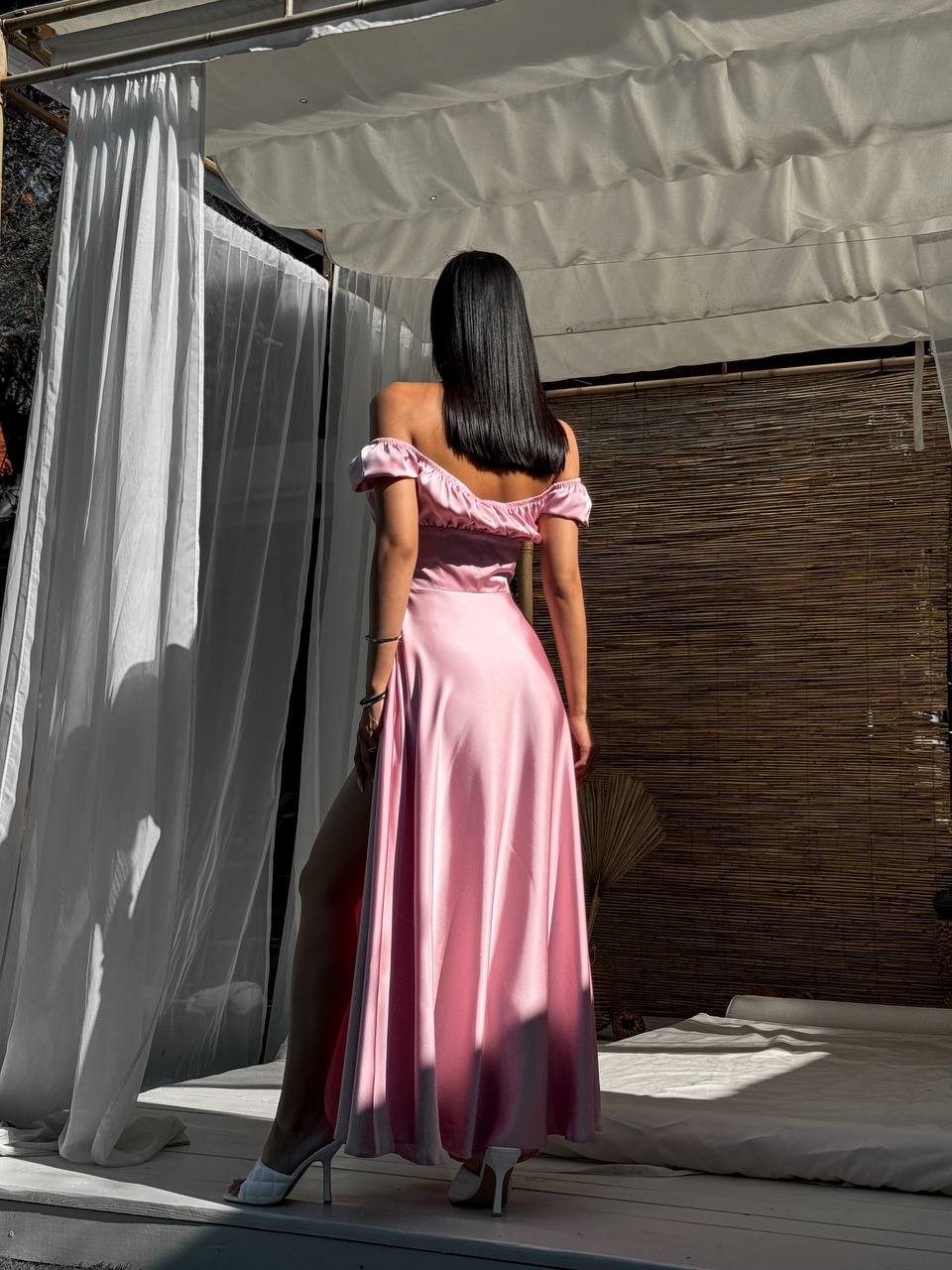 Woman in a pink dress standing in front of a white curtain