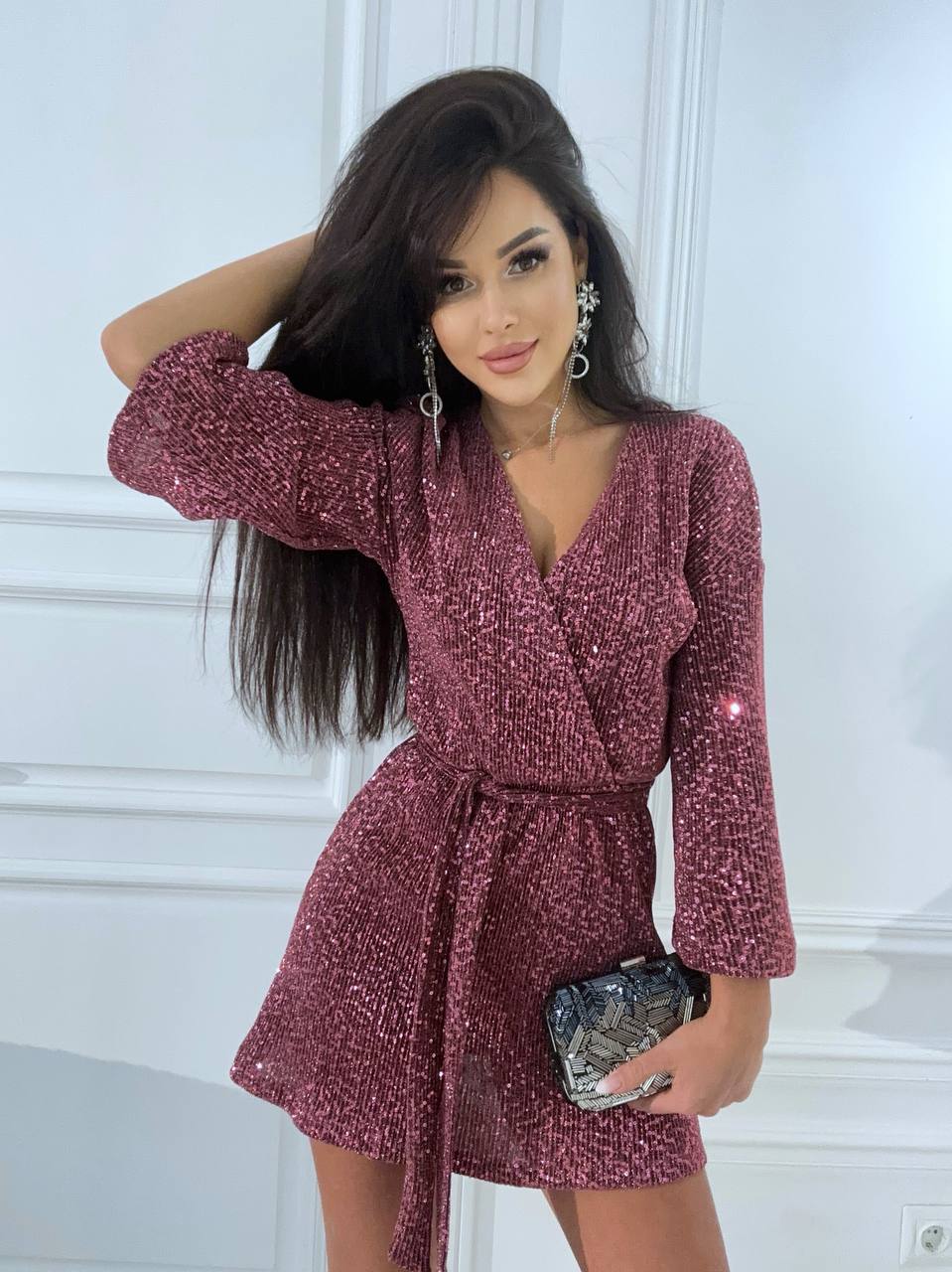 Woman wearing a sparkly burgundy dress against a white wall
