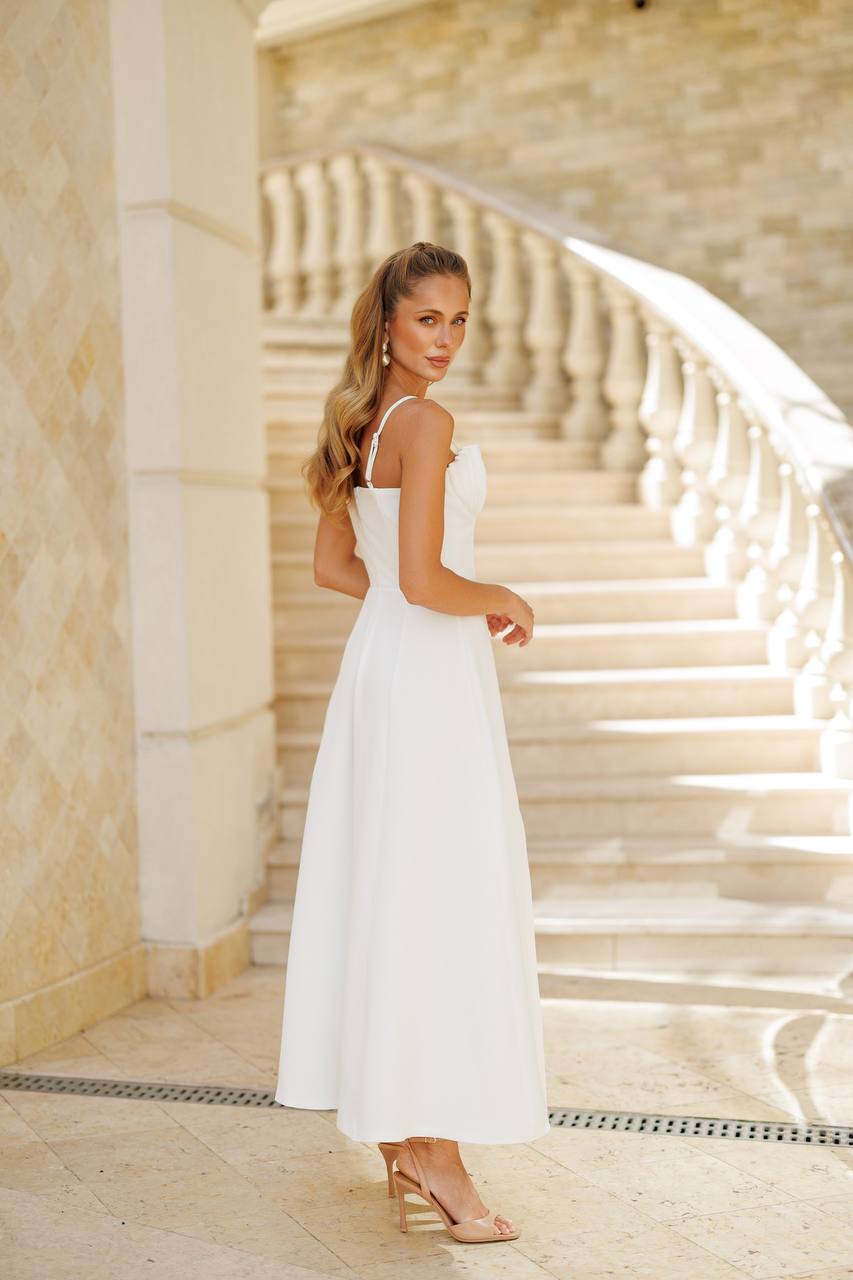 Woman in a white dress standing on a staircase with marble walls.