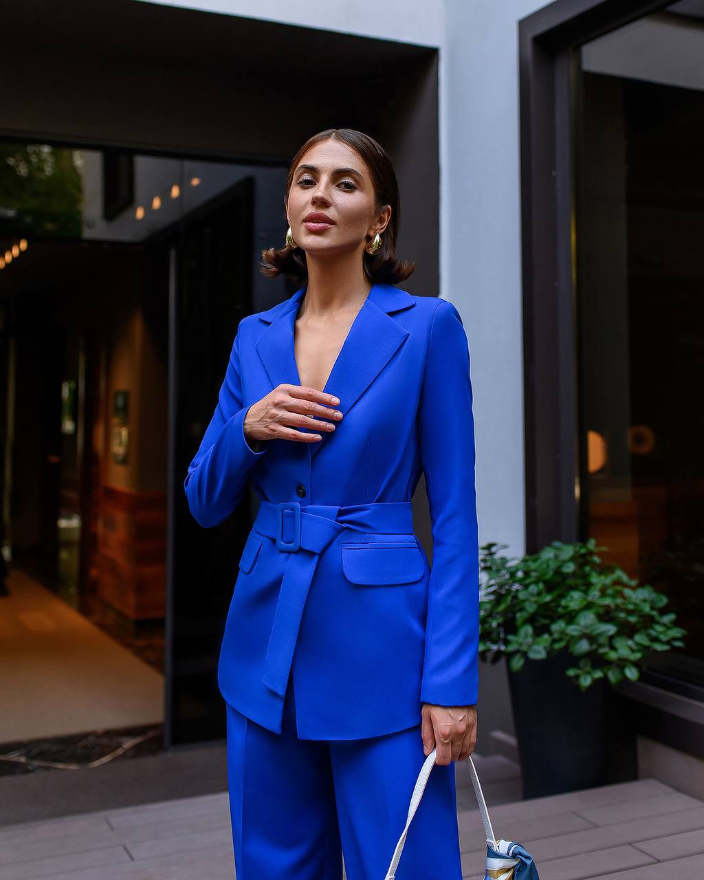 Woman in a blue suit standing outdoors with a building in the background