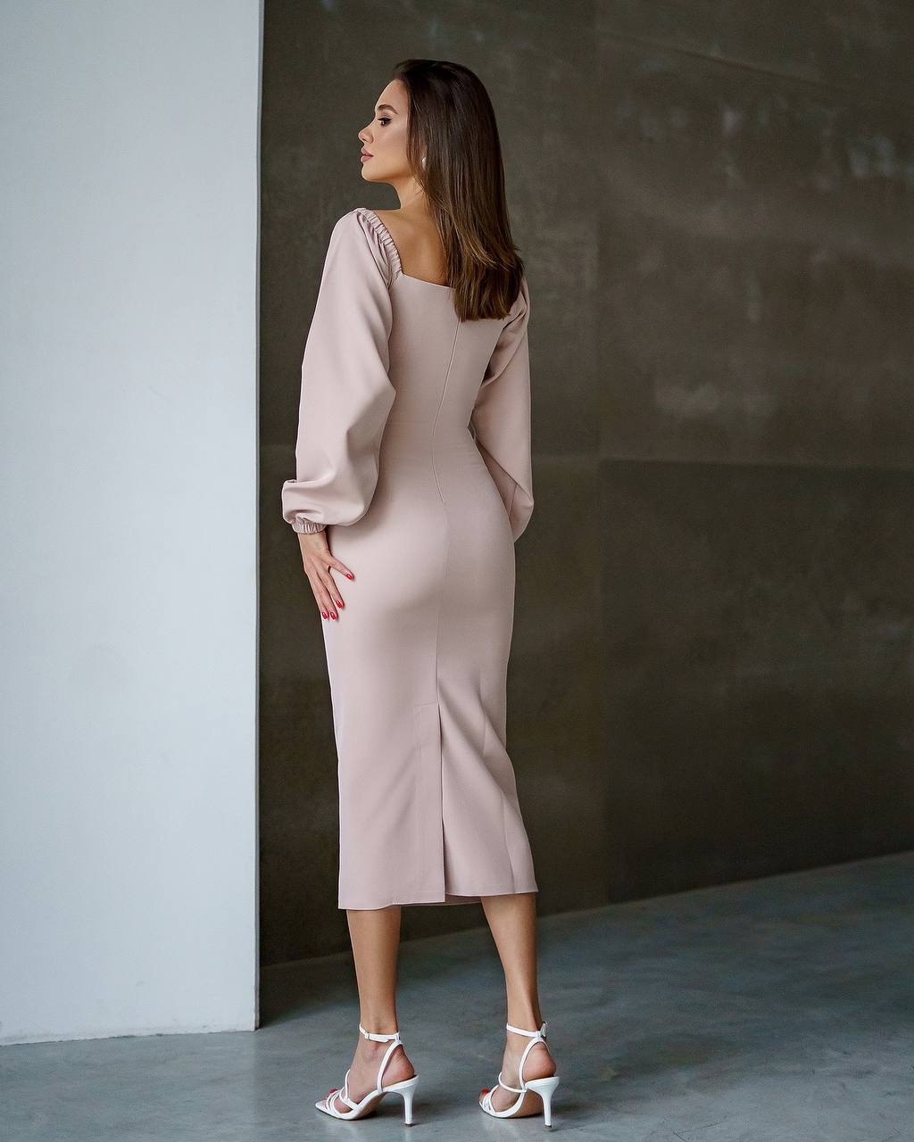 Woman wearing a light pink dress against a neutral wall