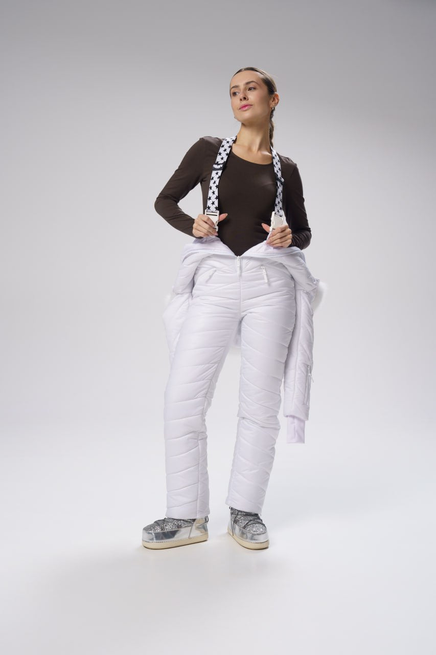 Person wearing white insulated pants with suspenders on a gray background