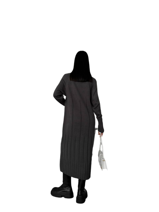 Person wearing a long dark coat holding a white bag on a white background