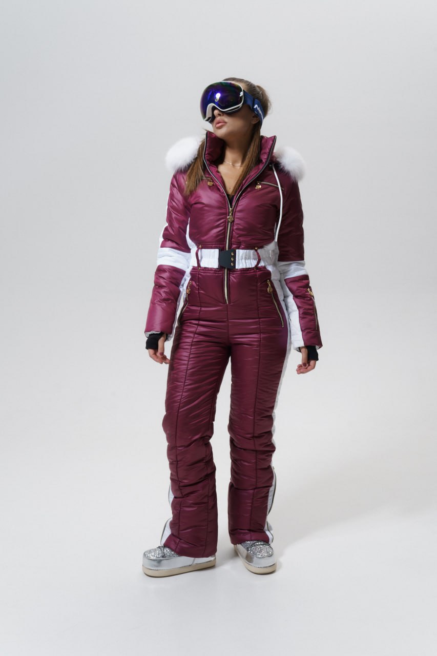 Person wearing a maroon ski suit with white accents on a white background
