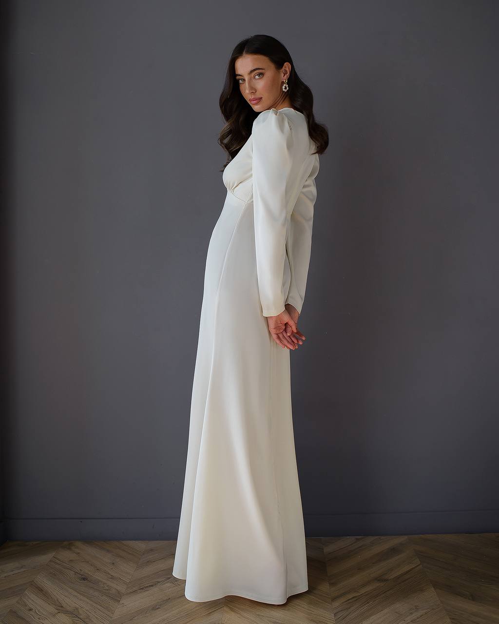 Woman wearing a long, light-colored dress against a plain background