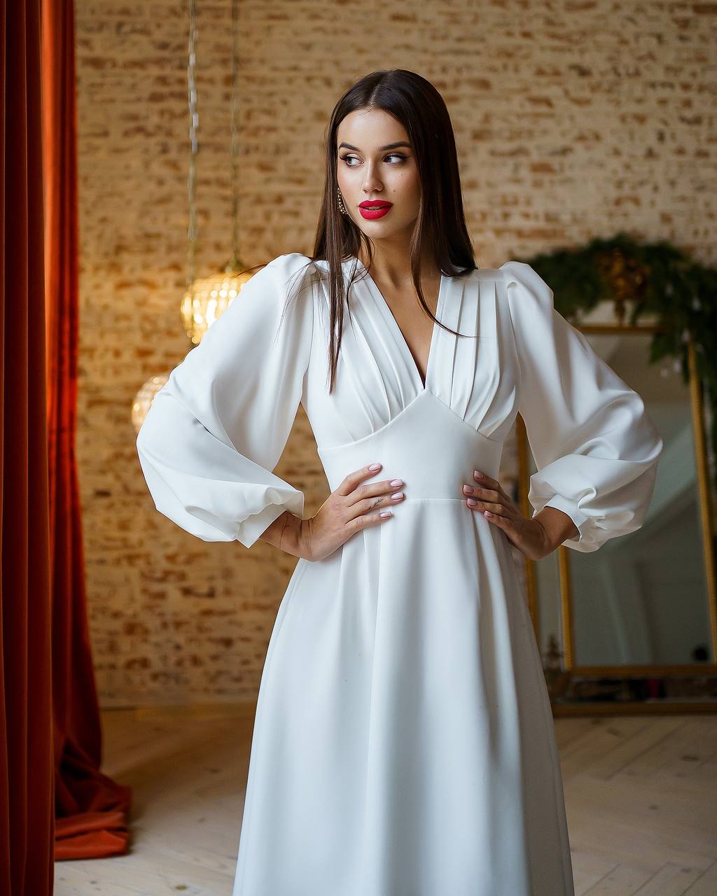 Woman wearing a white dress with long sleeves in an indoor setting.