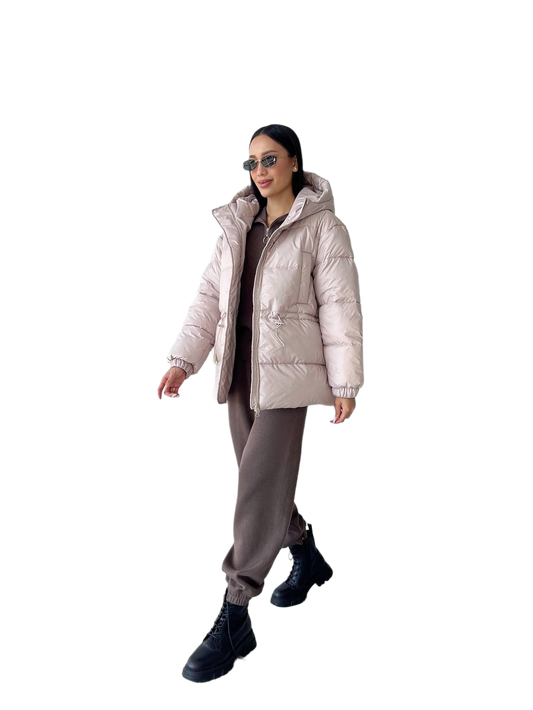 Person wearing a beige puffer jacket, gray pants, and black boots on a white background
