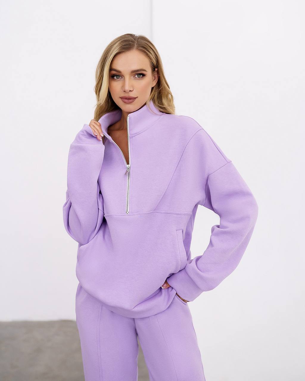 Woman wearing a lavender tracksuit against a white background