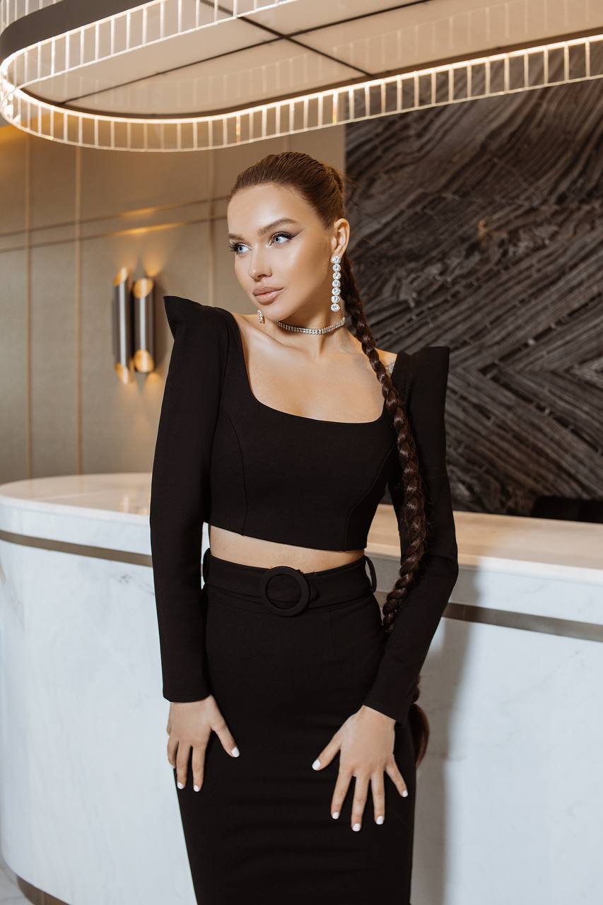 Woman in a black outfit standing in a stylish interior setting