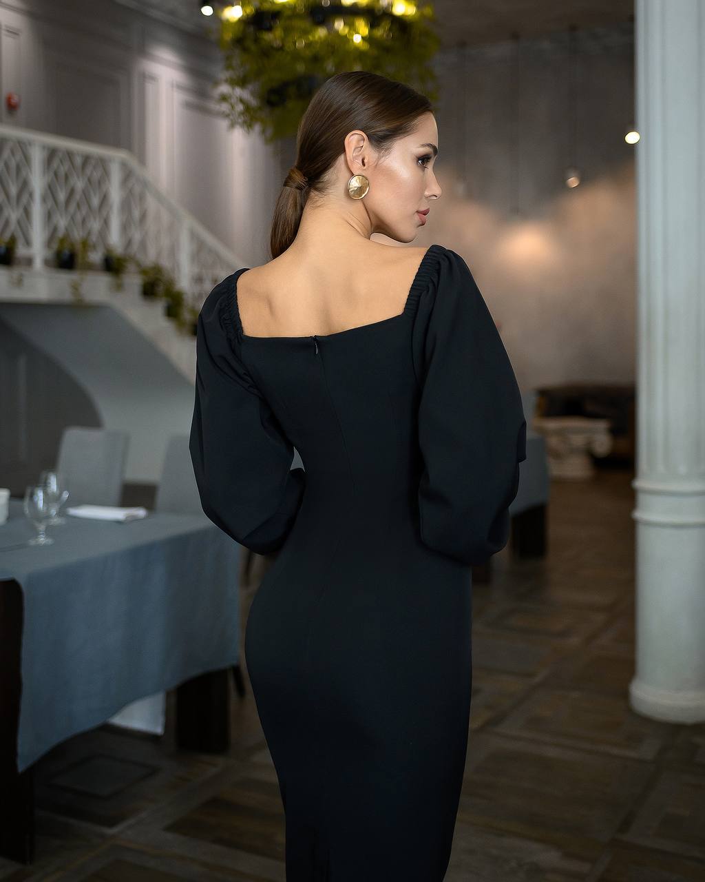 Woman in a black dress standing in a restaurant setting