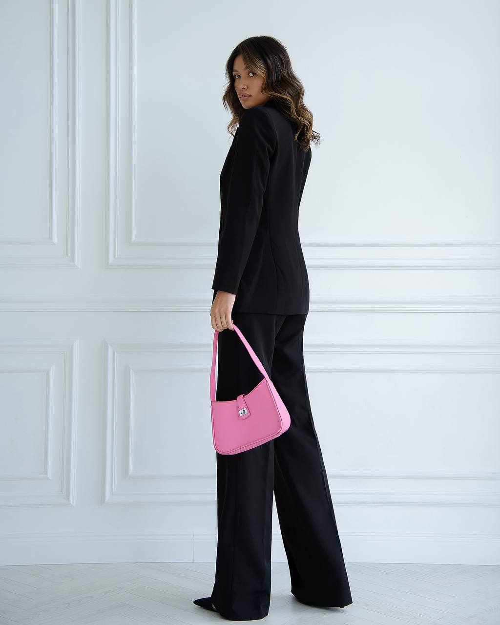 Person holding a pink handbag against a white wall