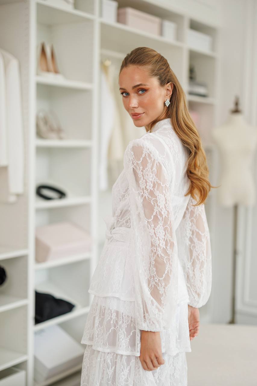 Woman wearing a white lace outfit in a room with shelves.