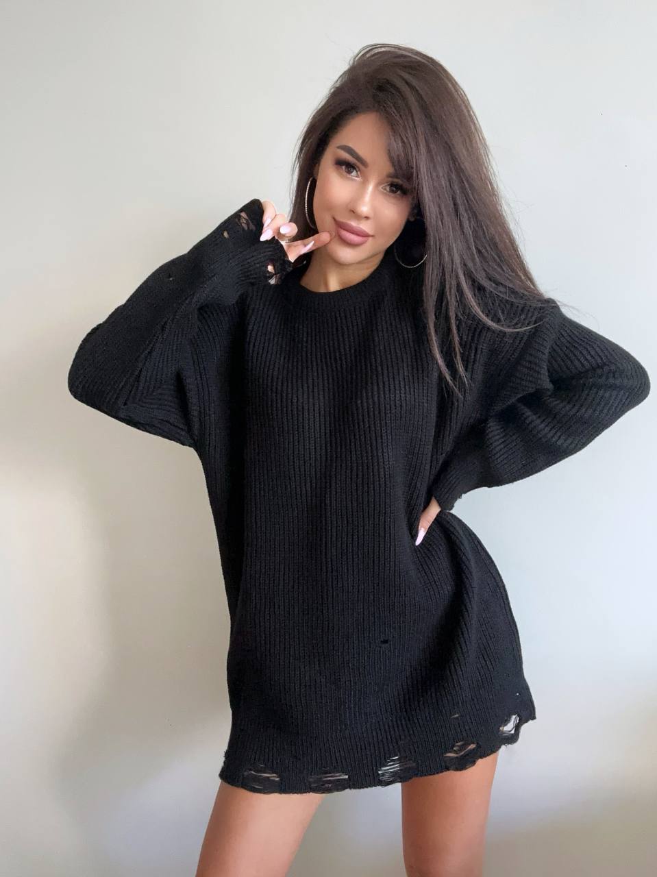 Woman wearing a black oversized sweater against a plain background