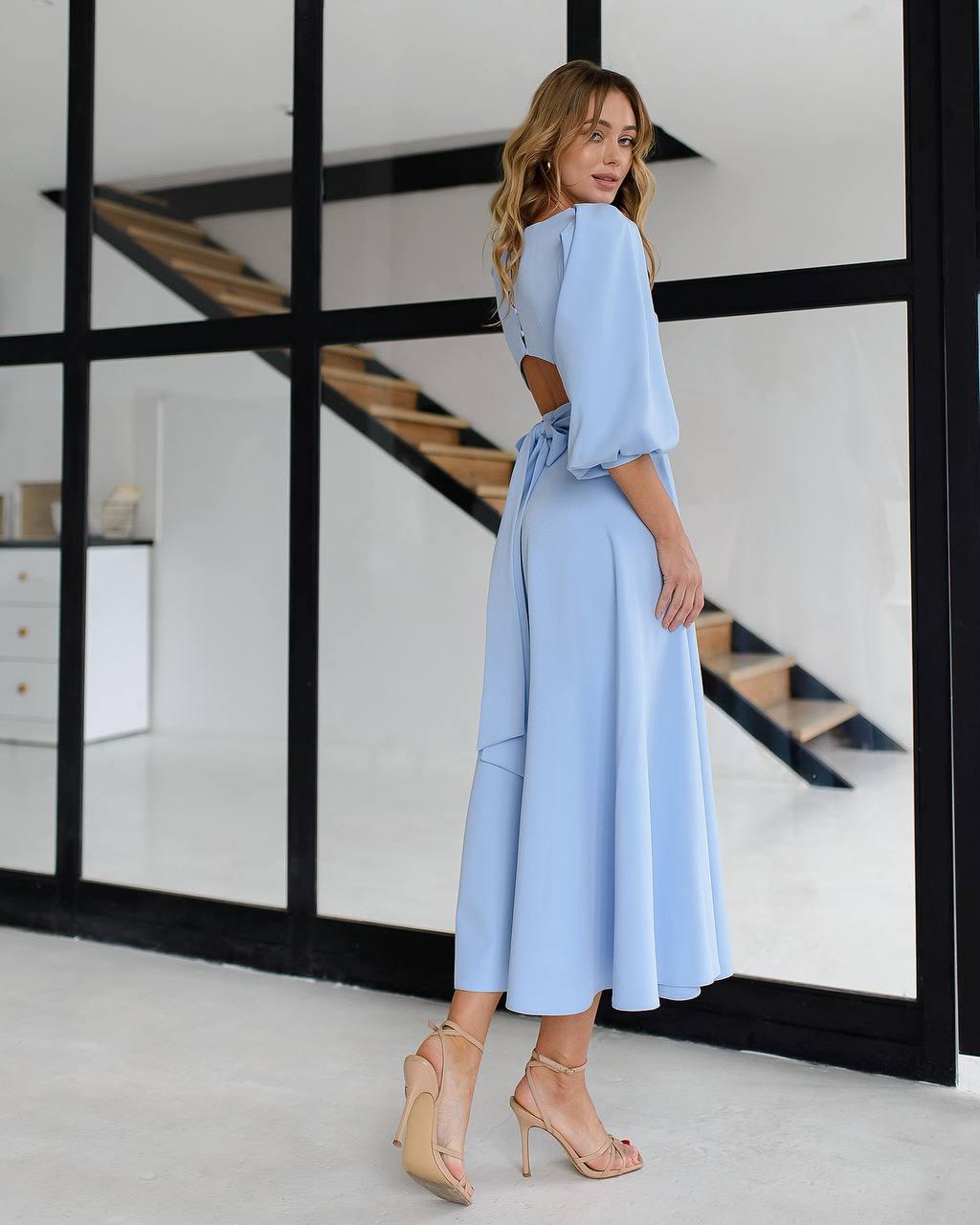 Woman wearing a light blue outfit standing in a modern interior setting.