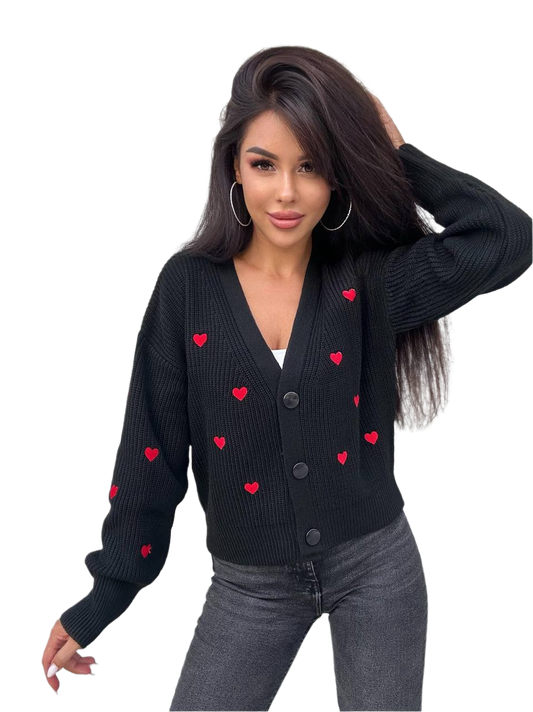 Woman wearing a black cardigan with red heart patterns on a white background