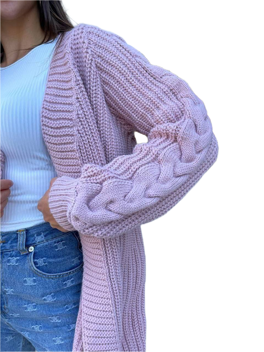 Person wearing a pink knitted cardigan over a white shirt and blue jeans on a white background