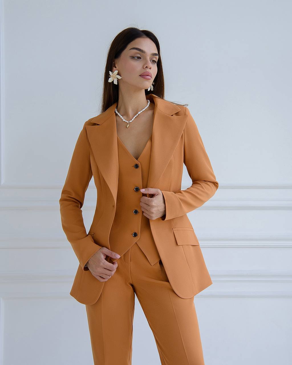 Woman wearing a mustard yellow suit against a white background