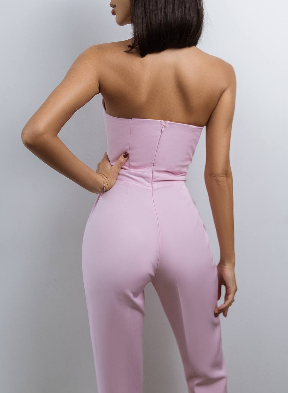 Pink strapless jumpsuit worn by a person against a plain background