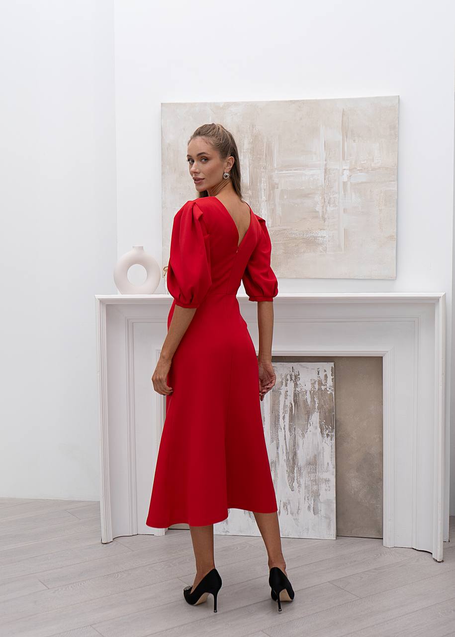 Woman in a red dress standing in a room with a fireplace and abstract art.