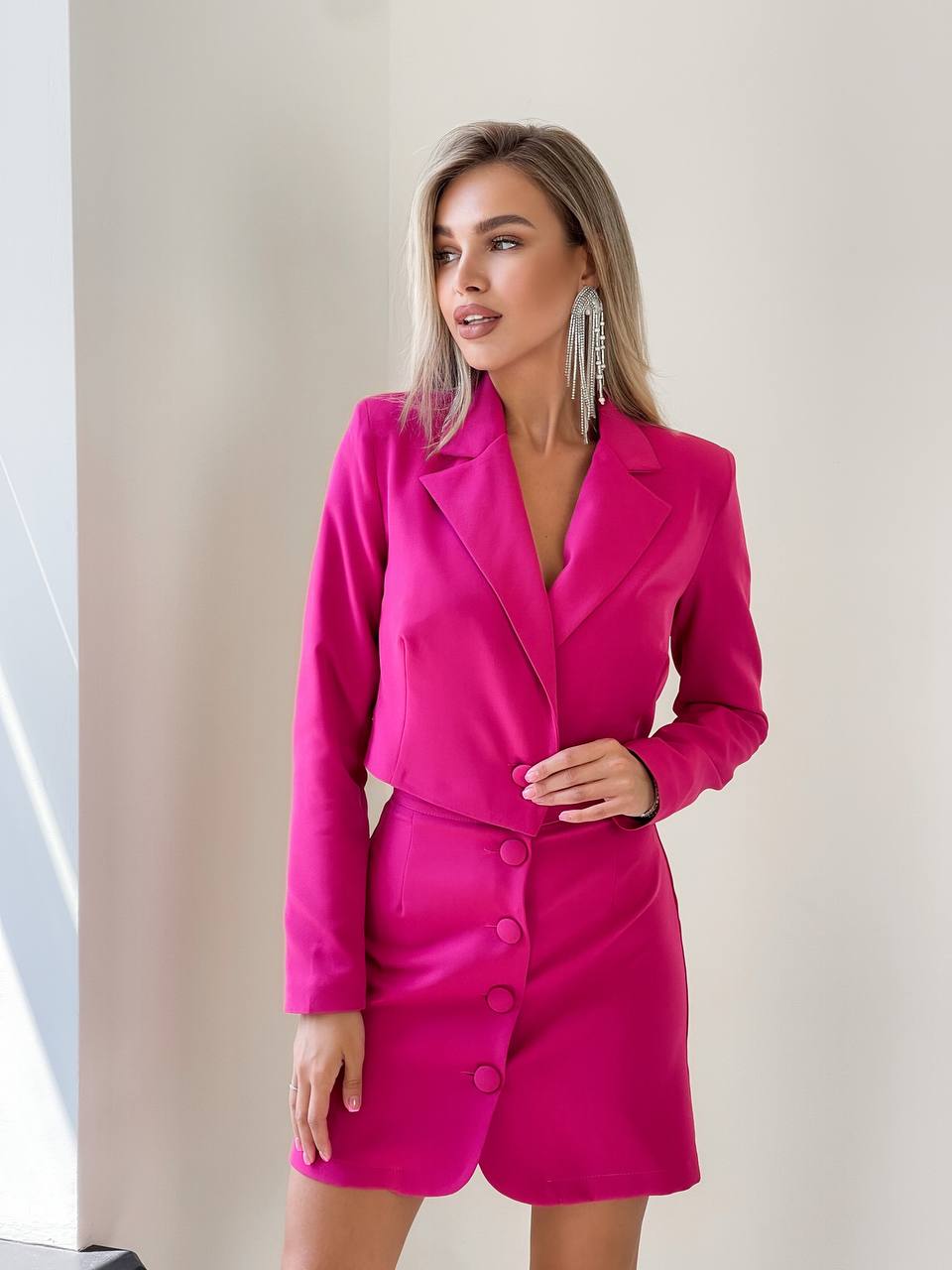 Woman wearing a bright pink suit with a plain background