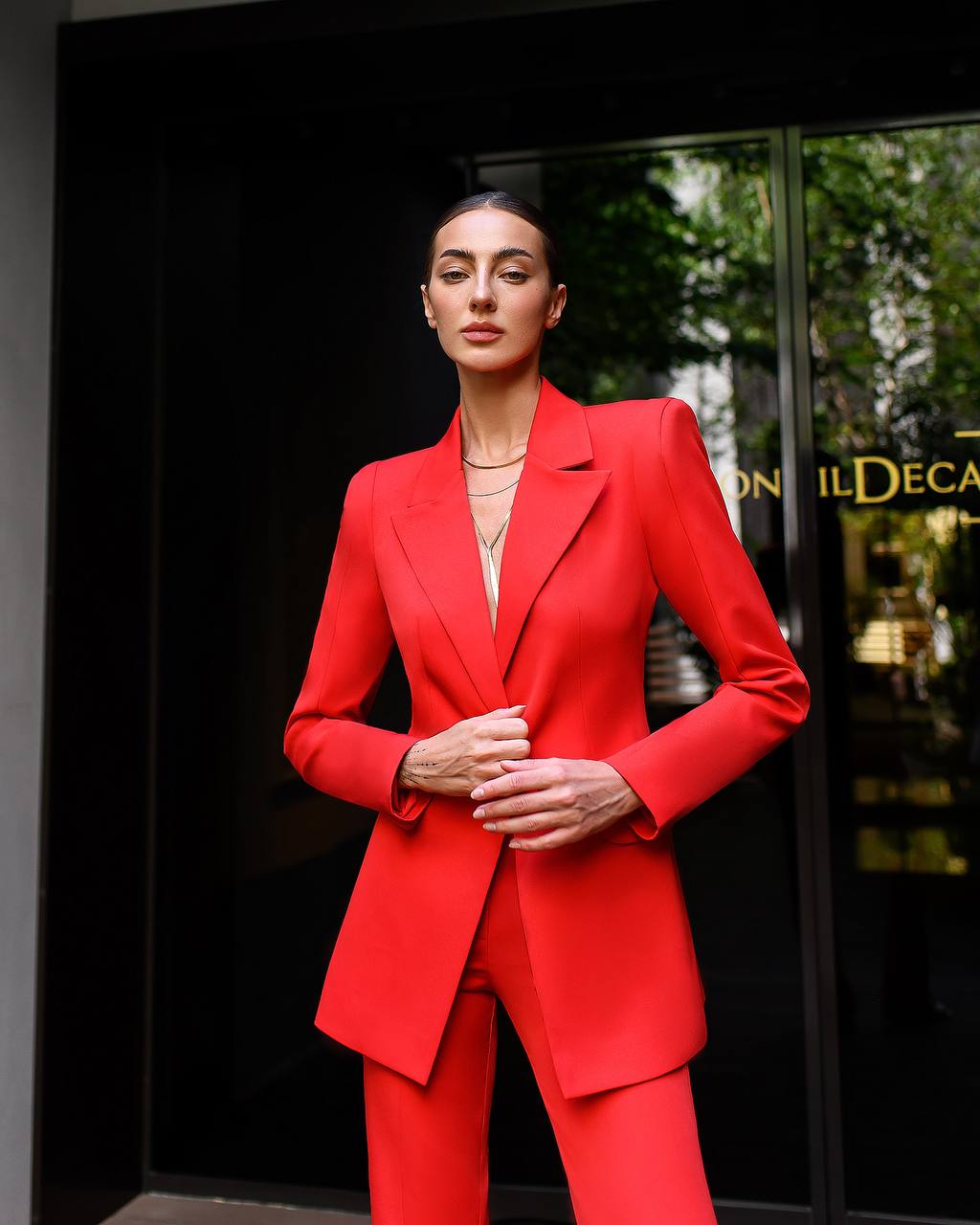 Woman wearing a red suit standing in front of a store entrance.