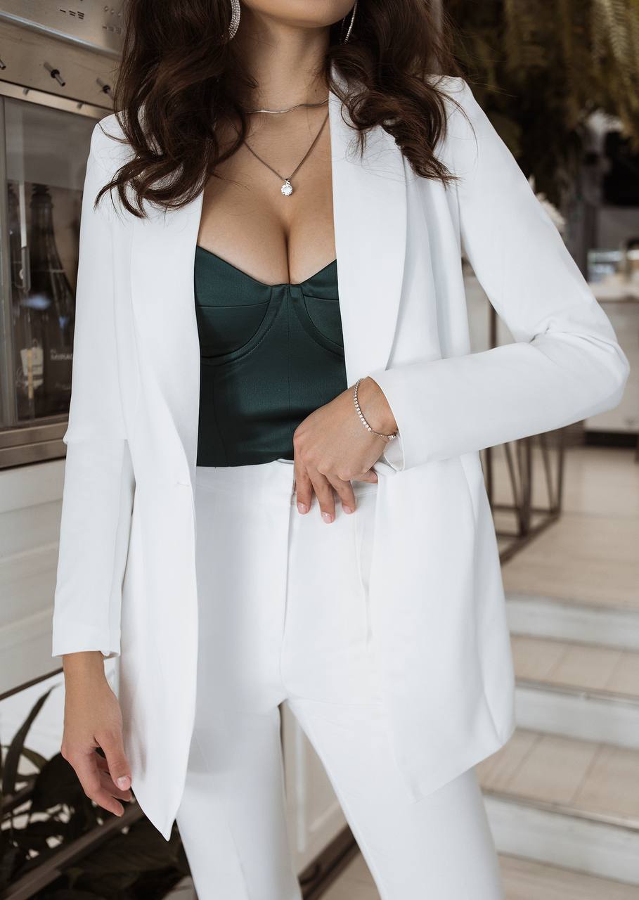 Person wearing a white blazer over a green top in an indoor setting
