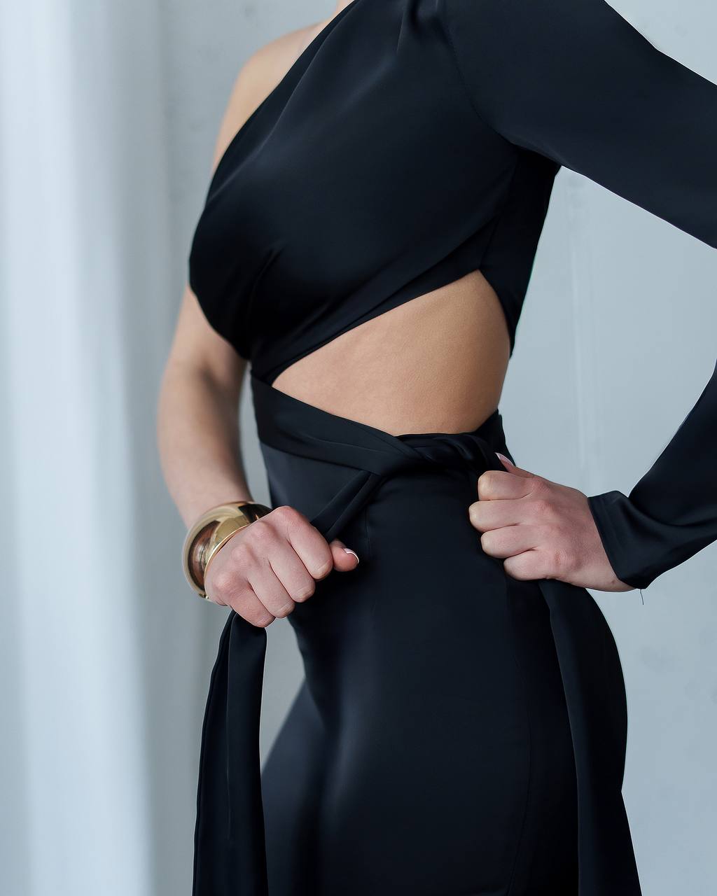 Person wearing a black outfit with a cutout design on a plain background
