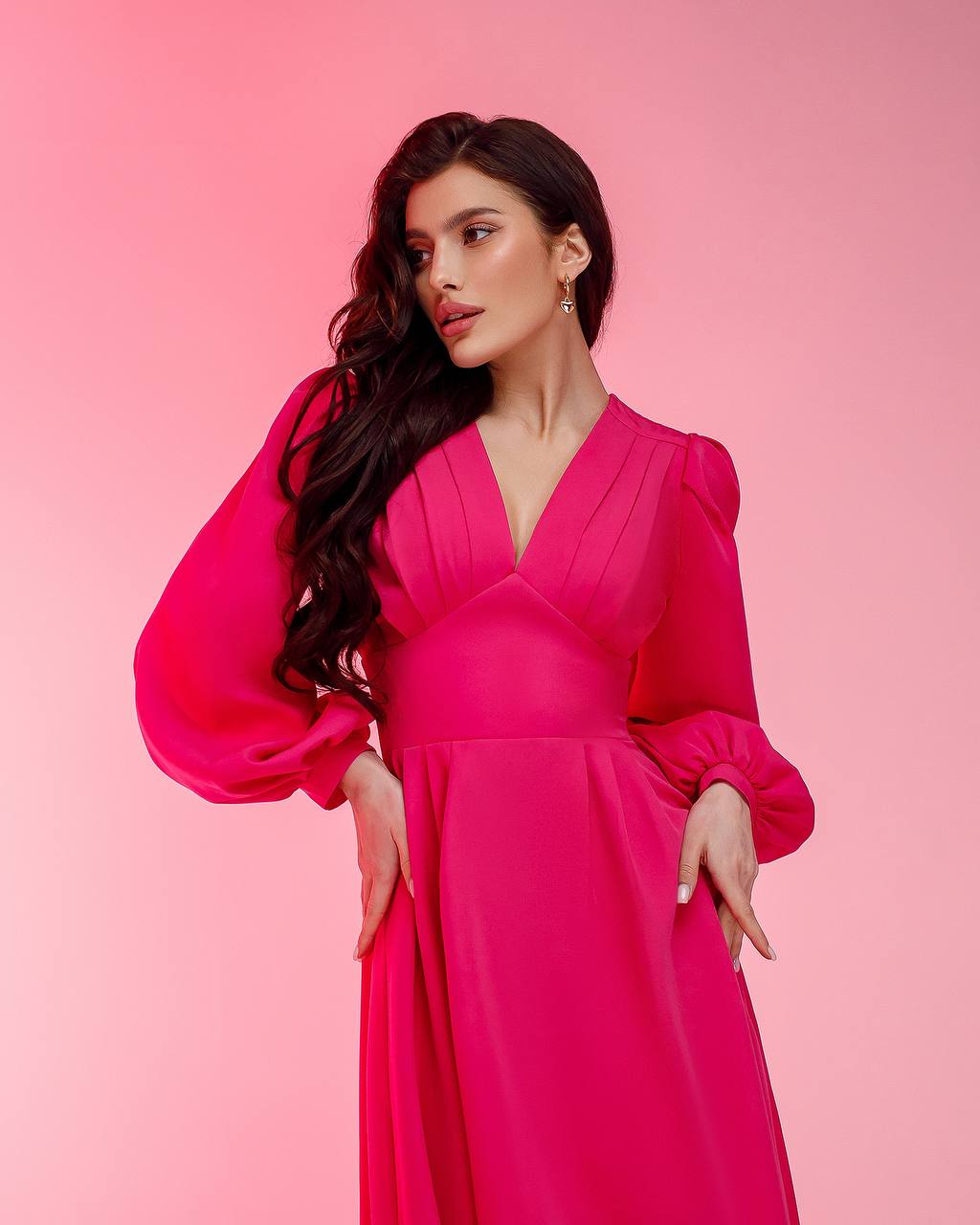Woman wearing a bright pink dress against a pink background