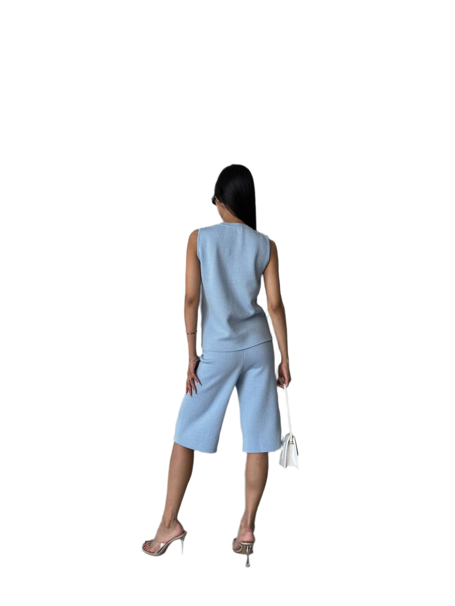 Woman wearing a light blue sleeveless top and shorts set on a white background
