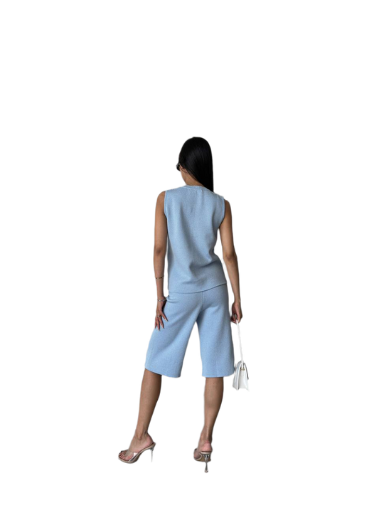 Woman wearing a light blue sleeveless top and shorts set on a white background