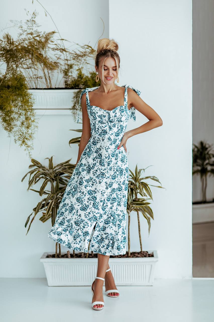 Woman in a floral dress standing in front of plants indoors