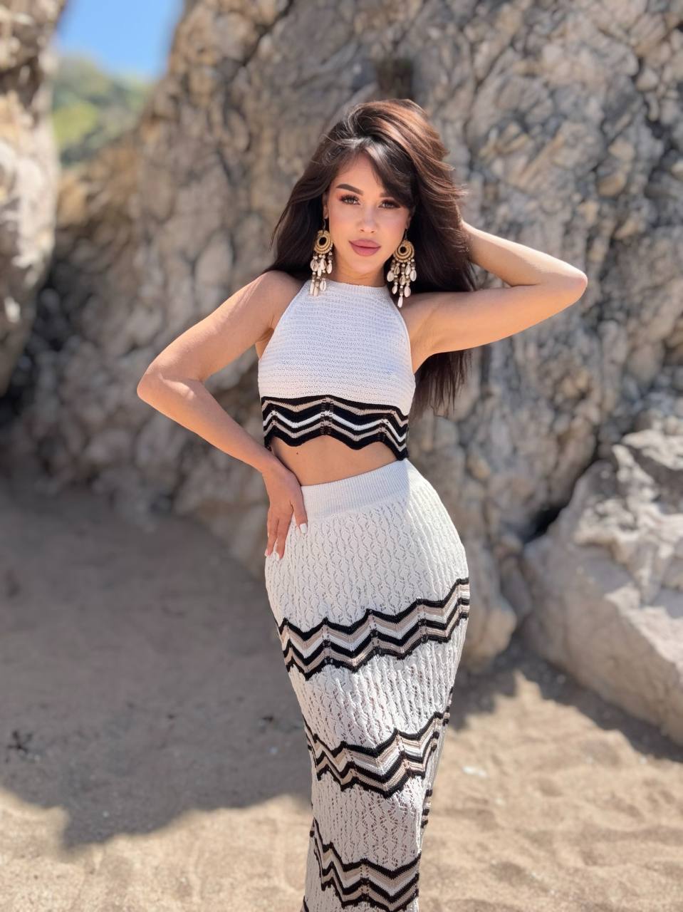 Woman in a black and white striped outfit standing against rocky terrain.