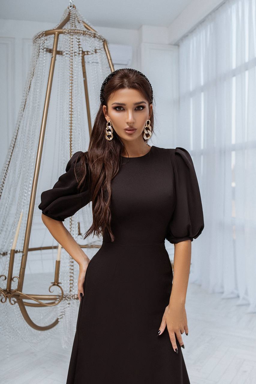 Woman in a black dress standing in a bright room with decorative elements.