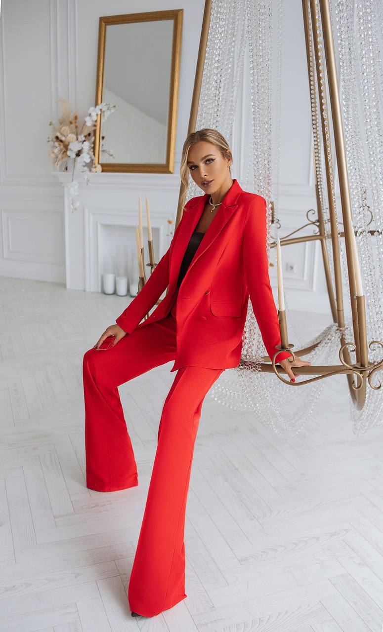 Woman in a red outfit sitting in a stylish room with decor elements.