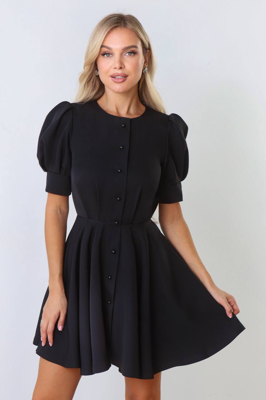 Woman wearing a black dress with puff sleeves against a white background