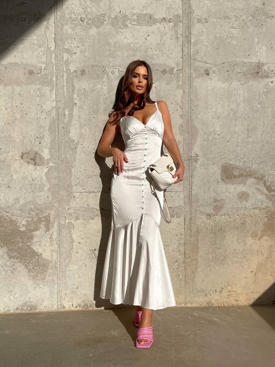 Woman in a white dress standing against a concrete wall