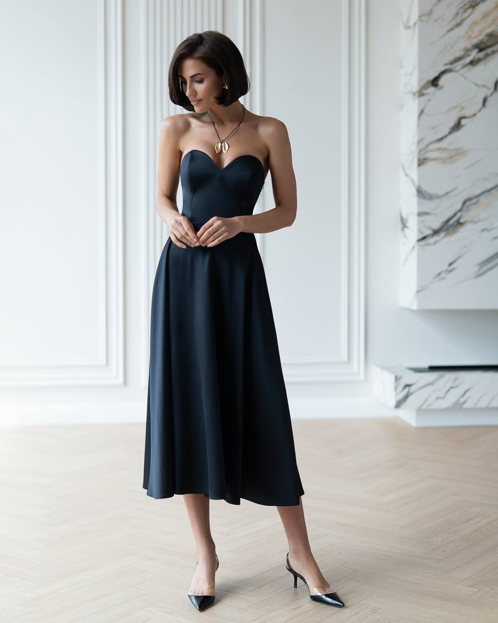 Woman wearing a black strapless dress in an elegant room.