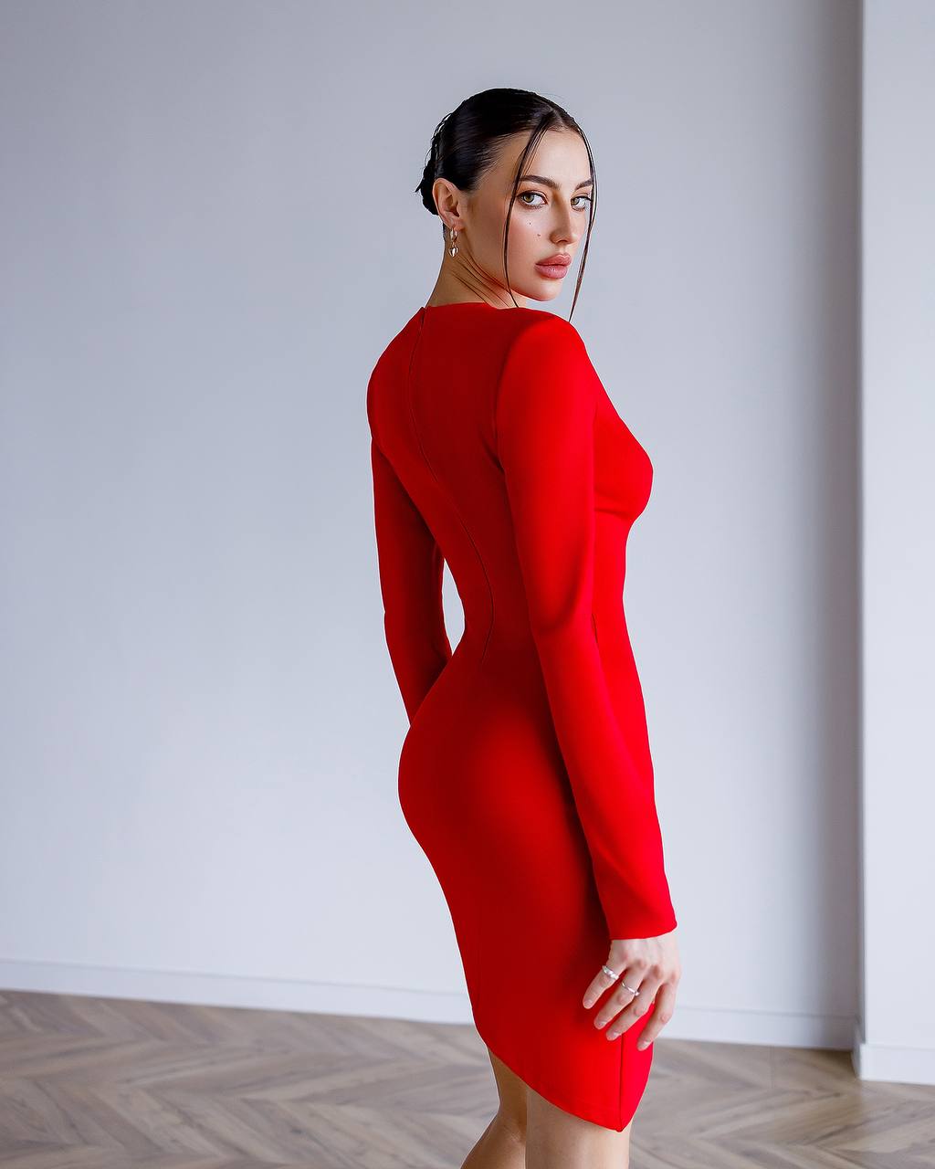 Woman wearing a red dress against a plain white wall.