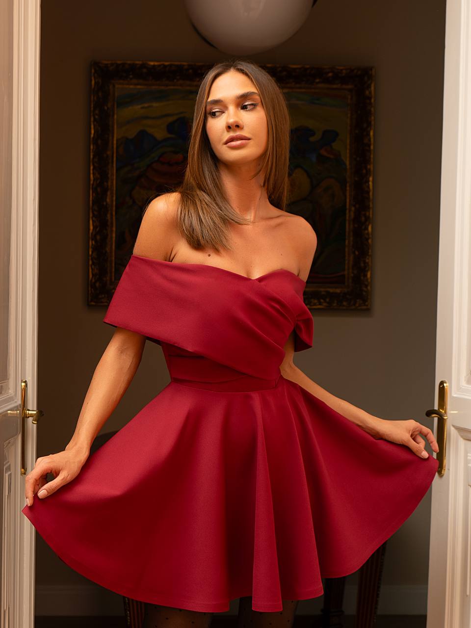 Woman wearing a red off-shoulder dress in an indoor setting.