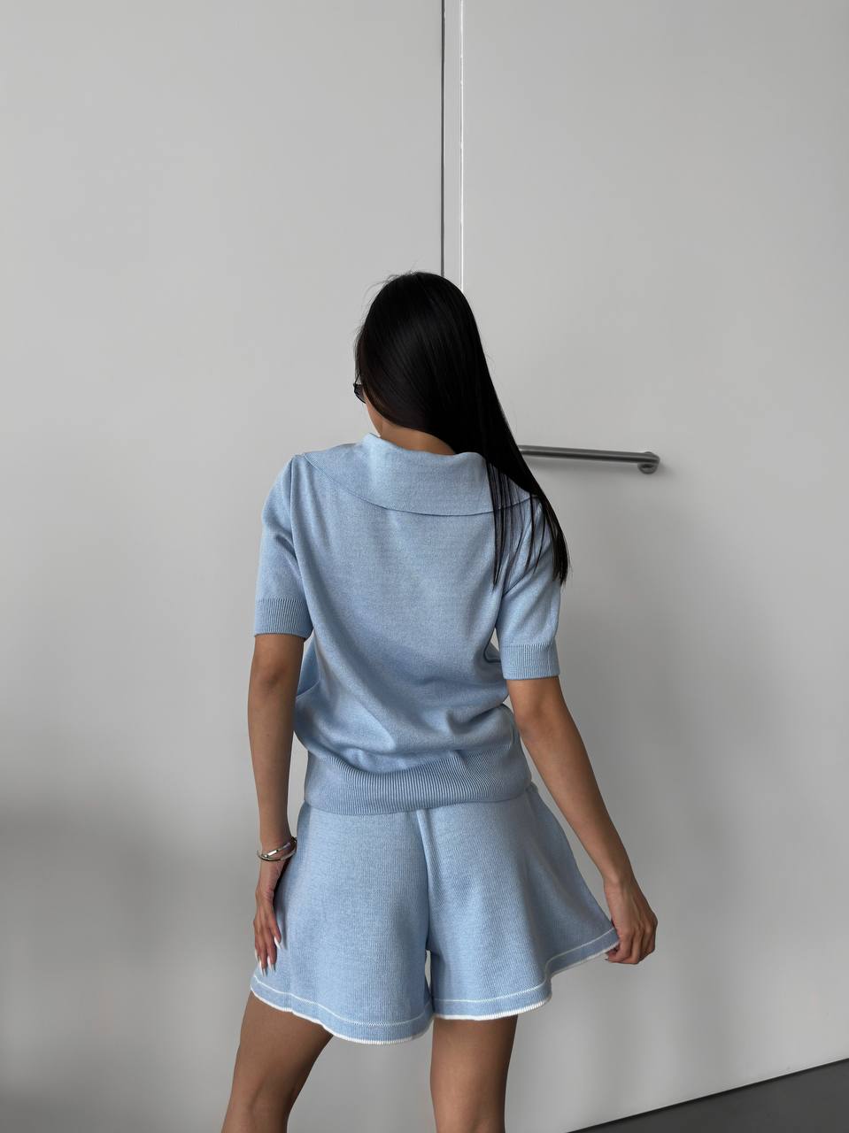 Person wearing a light blue tracksuit against a plain background
