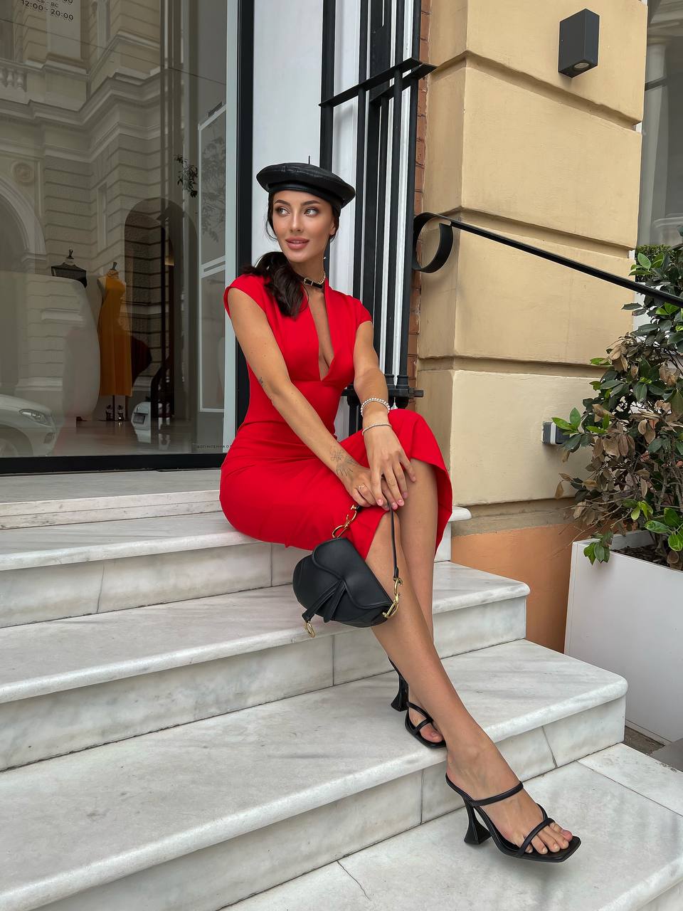 Woman in a red dress sitting on steps outside a building