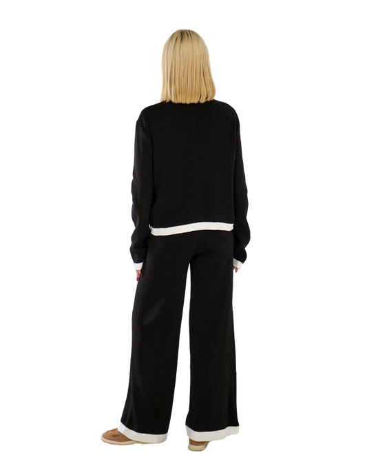 Woman wearing a black outfit with white trim on a white background